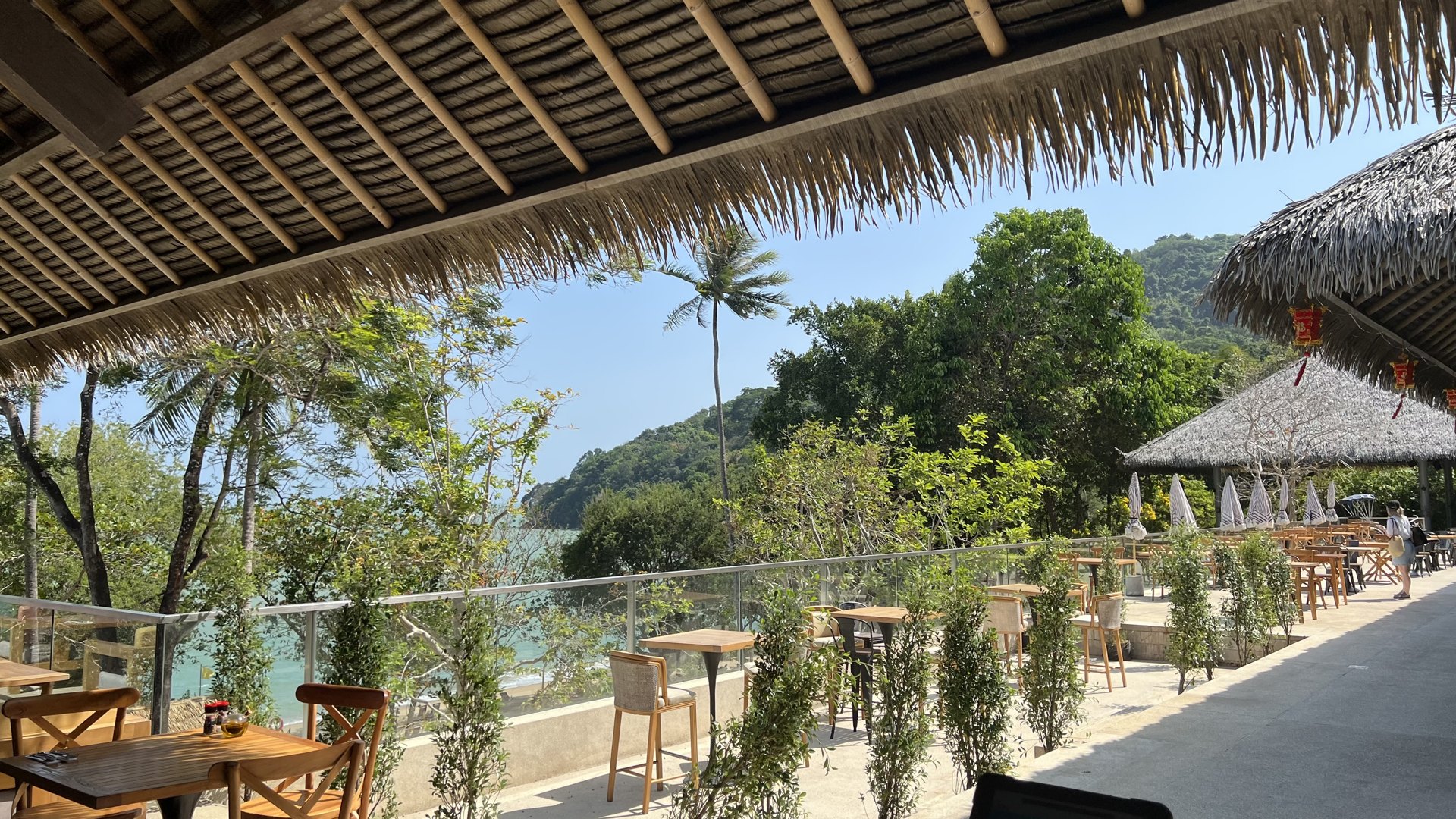Thatched restaurant terrace with wooden tables and a sea view
