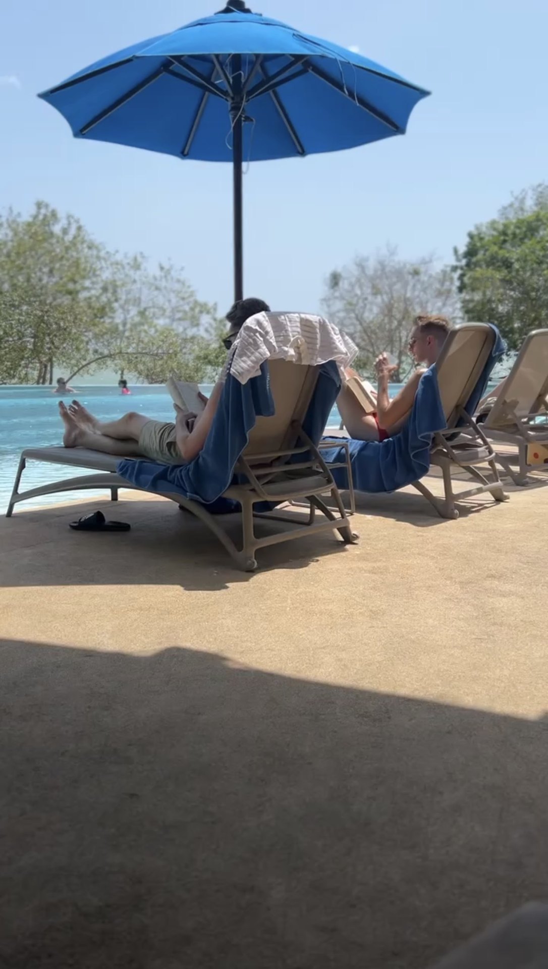 Sun loungers beneath a blue parasol beside the resort pool