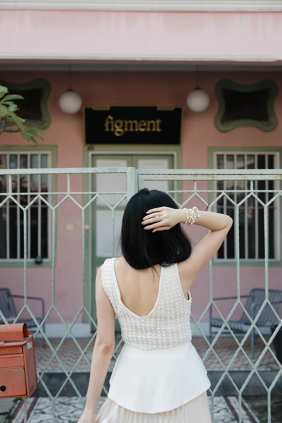 Back-facing portrait at a sage gate and pink façade