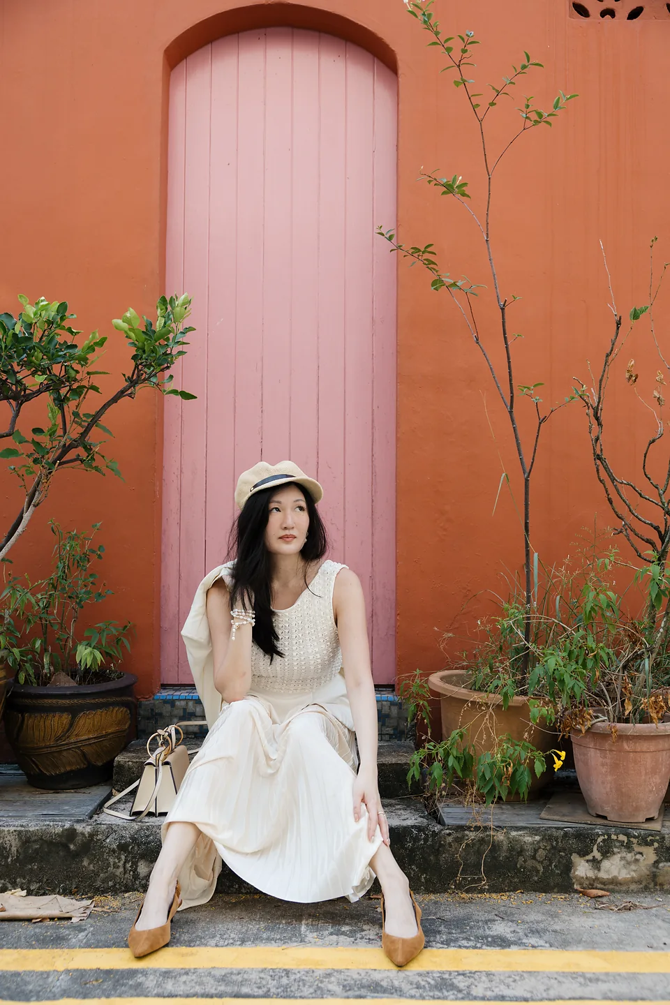 Ki with a hat at a pink arched doorway in a terracotta wall