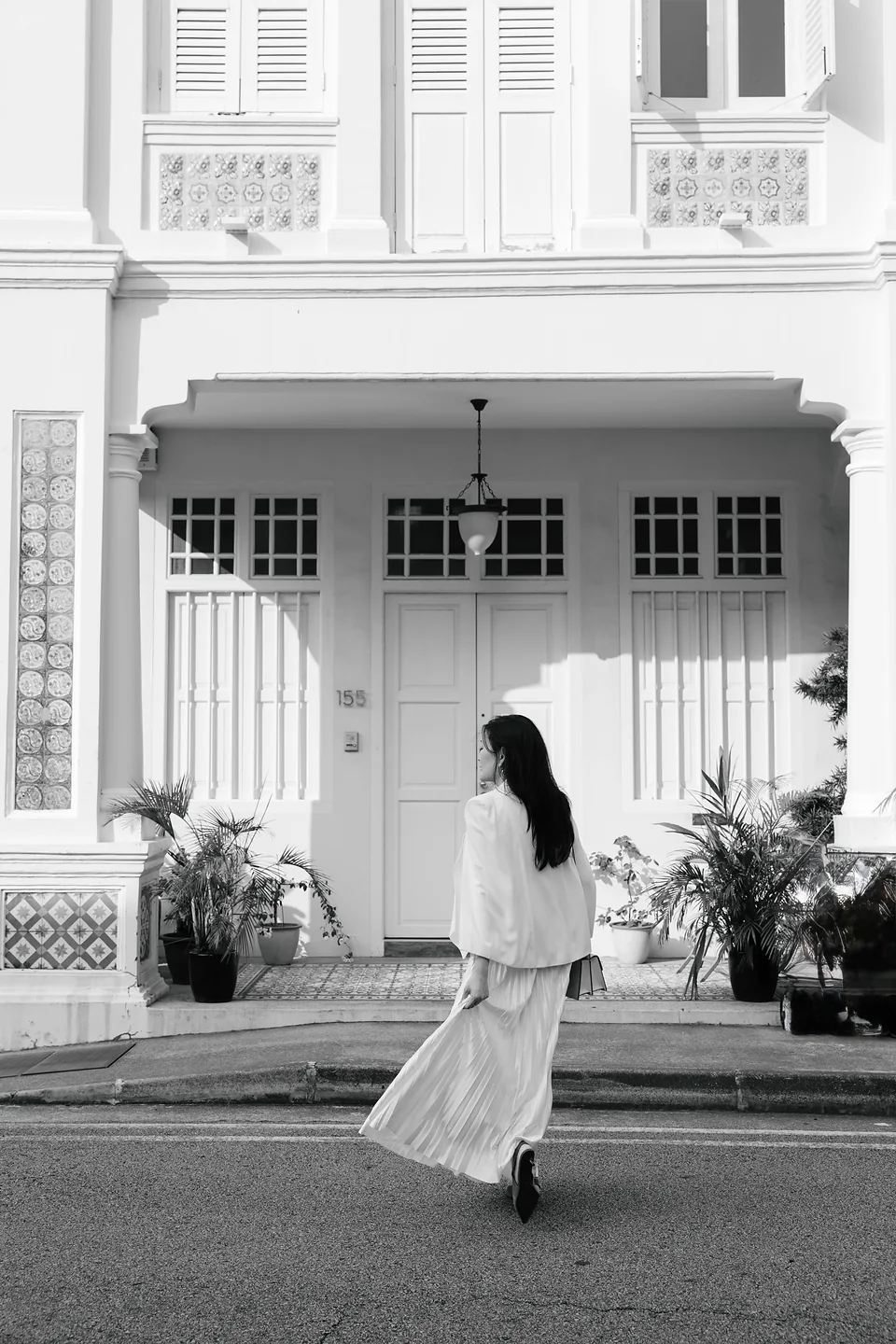 Black-and-white portrait of Ki in front of the heritage house, as featured in the video